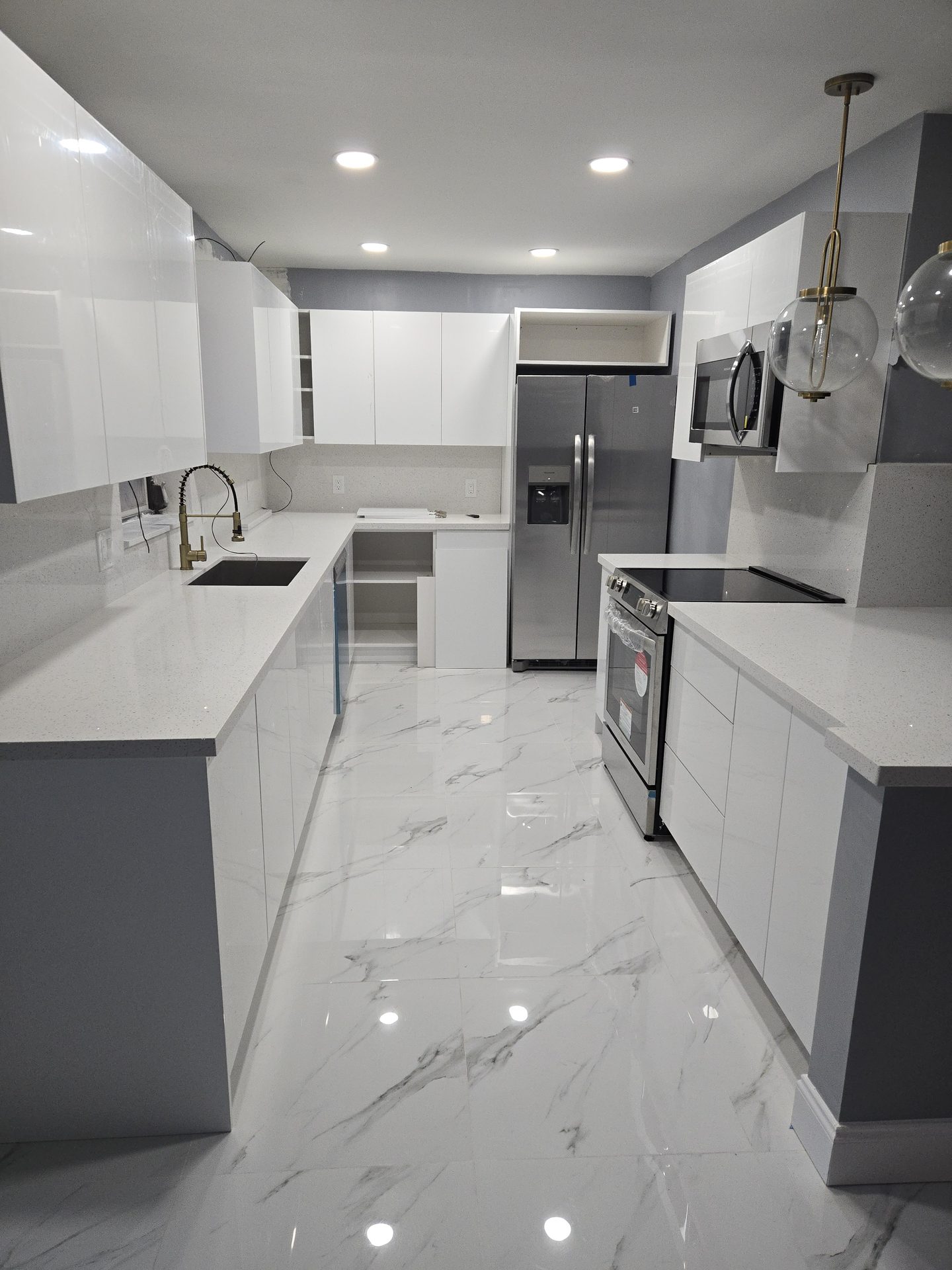 Kitchen remodeled by Firenova with white cabinets and marble-look porcelain tile floors